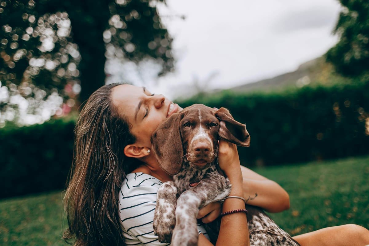 Một cô gái ôm chú chó con ngoài bãi cỏ